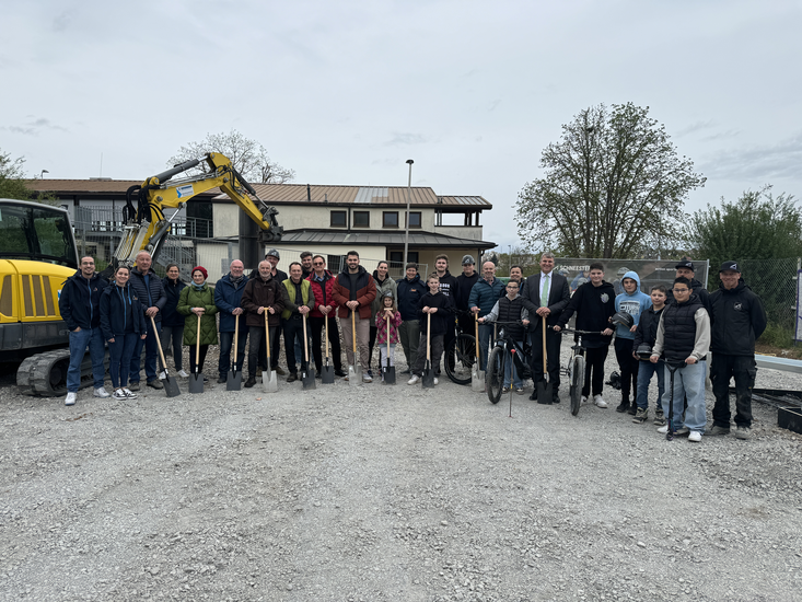 Viele Menschen mit einem Spaten an einer Baustelle.