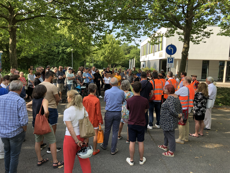 Menschen, die in einer Gruppe zusammenstehen und einem Vortrag lauschen.