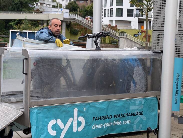 Mann, der ein Fahrrad in eine Fahrradwaschanlage stellt.