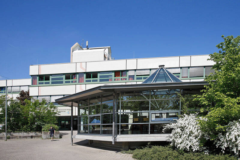 Lise-Meitner-Gymnasium von außen mit einer Glaspergola davor.