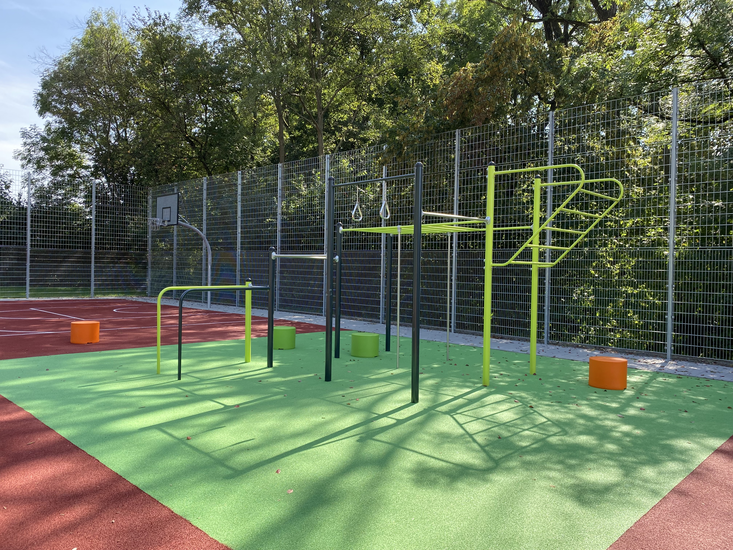 Sportanlage mit Calesthenics im freien. Im Hintergrund ein Basketballkorb.