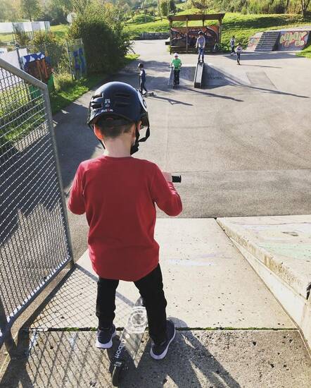 Kind an einer Abfahrtsrampe auf einer Skateanlage.