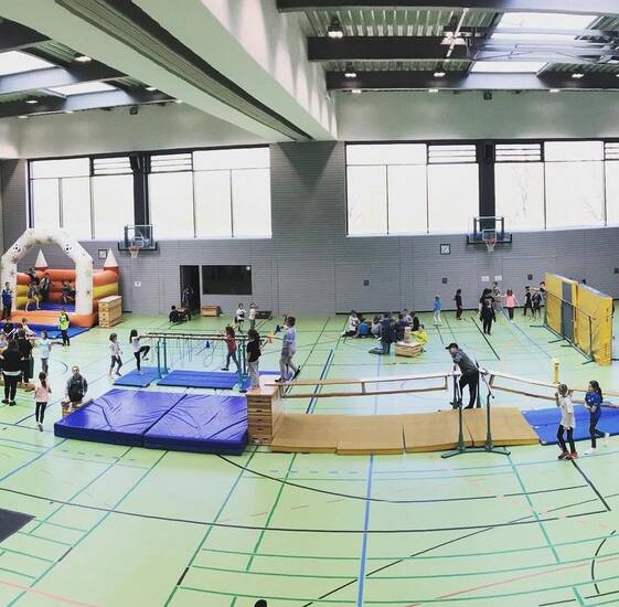 Kinder und Jugendliche, die in einer Sporthalle spielen.