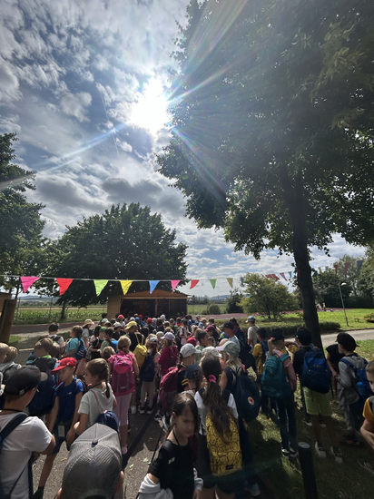 Eine Gruppe Kinder auf einem Platz, im Hintergrund die Sonne.