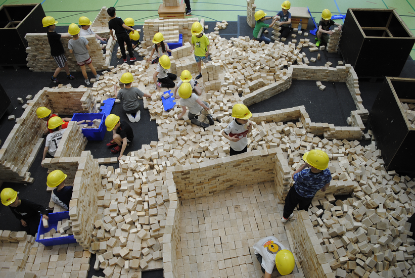 Kinder, die mit vielen Holzseteinen etwas bauen.