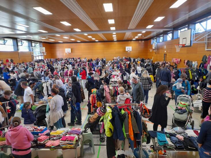 Menschen in einer Halle bei einem Kleidermarkt.