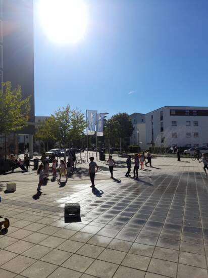 Kinder bei Sonnenschein auf einem Platz.