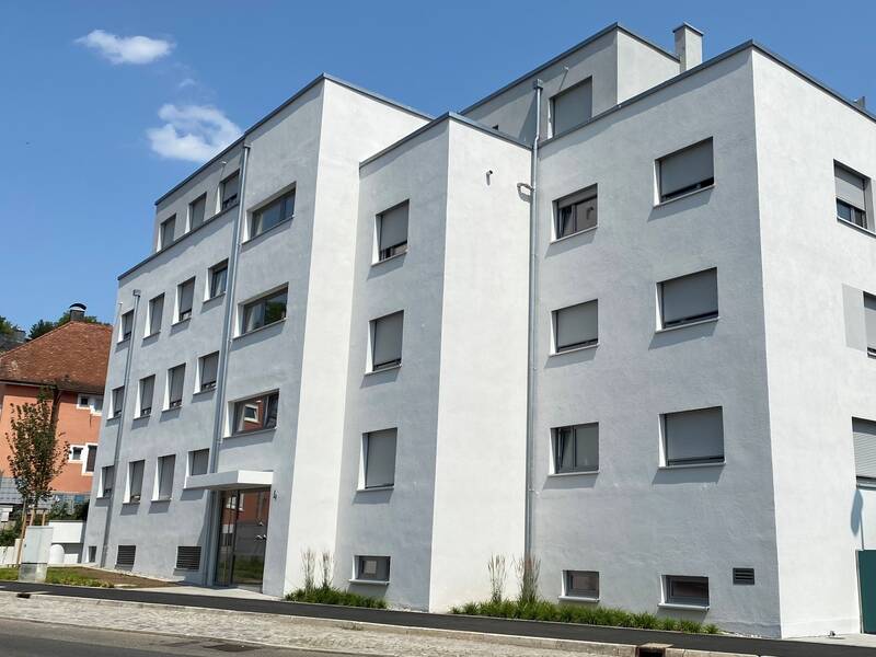 Mehrgeschössiges Wohnhaus bei blauem Himmel und Sonnenschein.