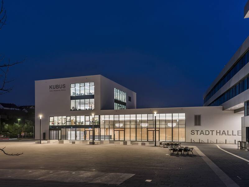 KUBUS und Stadthalle bei Nacht erleuchtet.