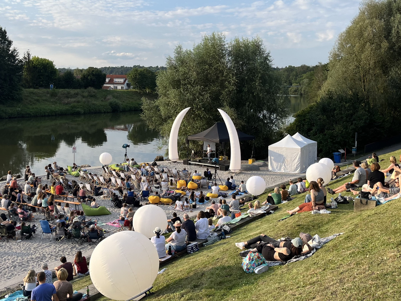 Neckarstrand mit Menschen gefüllt und einer Bühne am Rand.