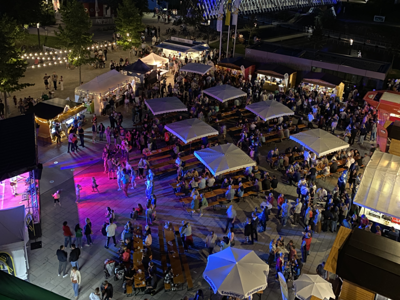 Der Marktplatz von oben bei Dämmerung mit vielen Besuchern. Eine Bühne und einige Stände und Sitzgelegenheiten sind aufgebaut.