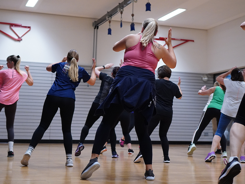 Eine Gruppe von Menschen macht in einem Fitnessstudio zusammen Aerobic-Übungen.